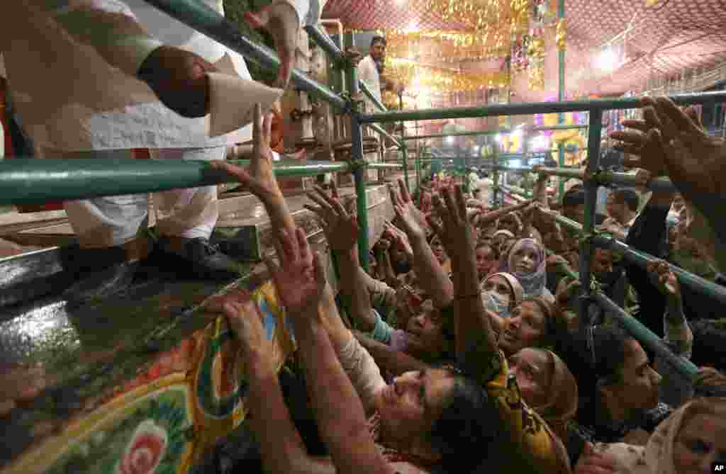 Women fight to get free milk at a distribution area during the celebrations of the three-day yearly festival of famous saint Al-Sheikh Ali Bin Usman Al-Hajveri known as Data Ganjbaksh at his shrine, in Lahore, Pakistan, Sept. 26, 2021.