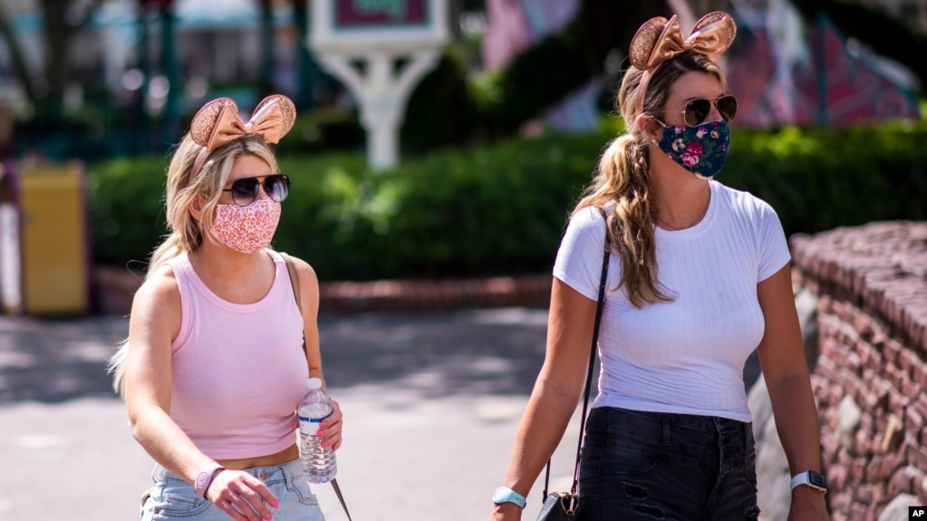 Para pengunjung Walt Disney World di Lake Buena Vista, Florida, mengenakan masker di tengah pandemi virus corona, 13 Agustus 2020. (Foto: Charles Sykes/Invision/AP) 
