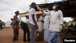 A health worker checks the temperature of a man entering Mali from Guinea at the border checkpoint, Oct. 2, 2014. (REUTERS/Joe Penney)