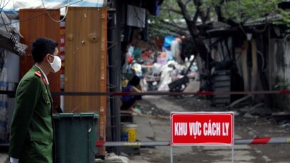 Một công an đeo khẩu trang chống khuẩn đứng gác bên ngoài khu cách ly người nhiễm virus corona ở Hà Nội hôm 13/3. Chính phủ Việt Nam quyết tâm giữ cho số ca nhiễm Covid-19 dưới mức 1.000.