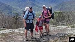 In this April 11, 2021, family photograph provided by Joshua Sutton, 5-year-old Harvey Sutton, center, poses with his mom Cassie, right, and dad Joshua, mountain top in Three Ridges, Virginia, while hiking the Appalachian Trail with his mom and dad.