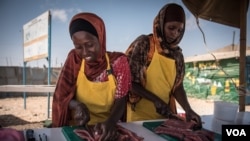 Women slice fresh fish in thin strips to dry for eventual sale as part of a Food and Agriculture Organization program to boost Somalia's fishing industry, in late March 2018. (J. Patinkin/VOA)