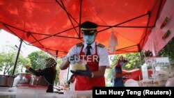 Mantan pilot Malaysia Azrin Mohamad Zawawi menyiapkan makanan di warung makannya di Subang Jaya, Malaysia, 7 November 2020. (Foto: REUTERS/Lim Huey Teng)