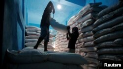 Laborers lift a sack filled with sugar to load it onto a handcart at a wholesale market in Kolkata, Feb. 1, 2018. 