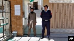 A Pakistani police officer stands guard with a worker of a religious group at the entrance to a mosque in Islamabad, Pakistan, March 6, 2019.