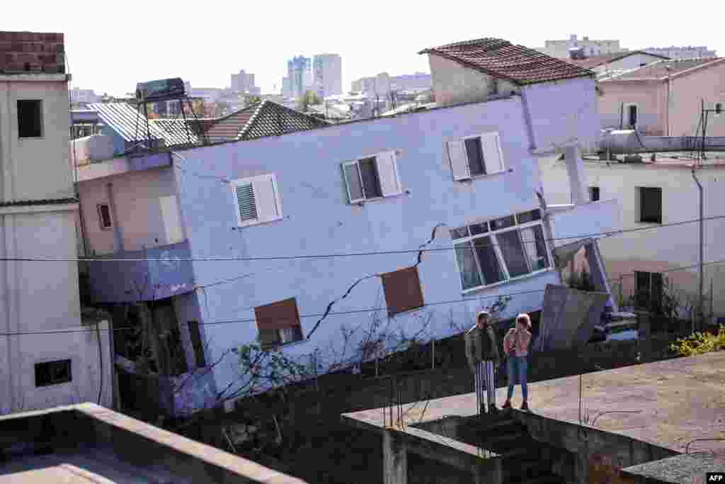 People stand in front of a collapsed building in the town of Durres, western Albania after an earthquake hit.