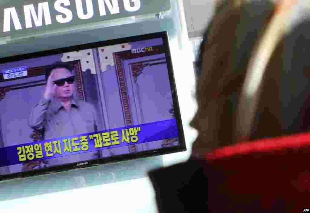 Một phụ nữ Nam Triều Tiên tại một nhà ga ở Seoul xem TV nói về cái chết của Kim Jong Il, 19 tháng 12.