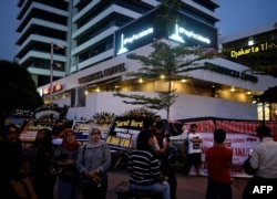 FILE - A "Pray for Jakarta" message (top) is displayed on a screen as Indonesians gather outside the damaged Starbucks coffee shop in central Jakarta on Jan. 17, 2016 following the deadly gun and bomb attacks that rocked the city on Jan. 14.