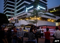 A "Pray for Jakarta" message (top) is displayed on a screen as Indonesians gather outside the damaged Starbucks coffee shop in central Jakarta on Jan. 17, 2016 following the deadly gun and bomb attacks that rocked the city on Jan. 14.