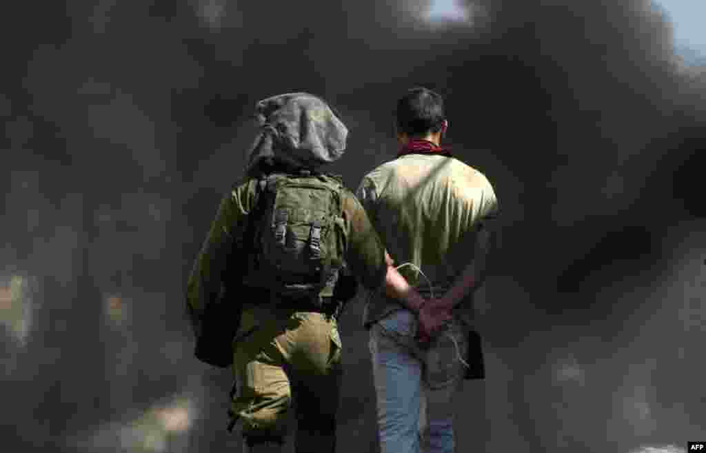 An Israeli soldier escorts a detained Spanish activist during clashes between Palestinian protesters and Israeli forces in the village of Kfar Qaddum, in the Israeli-occupied West Bank.