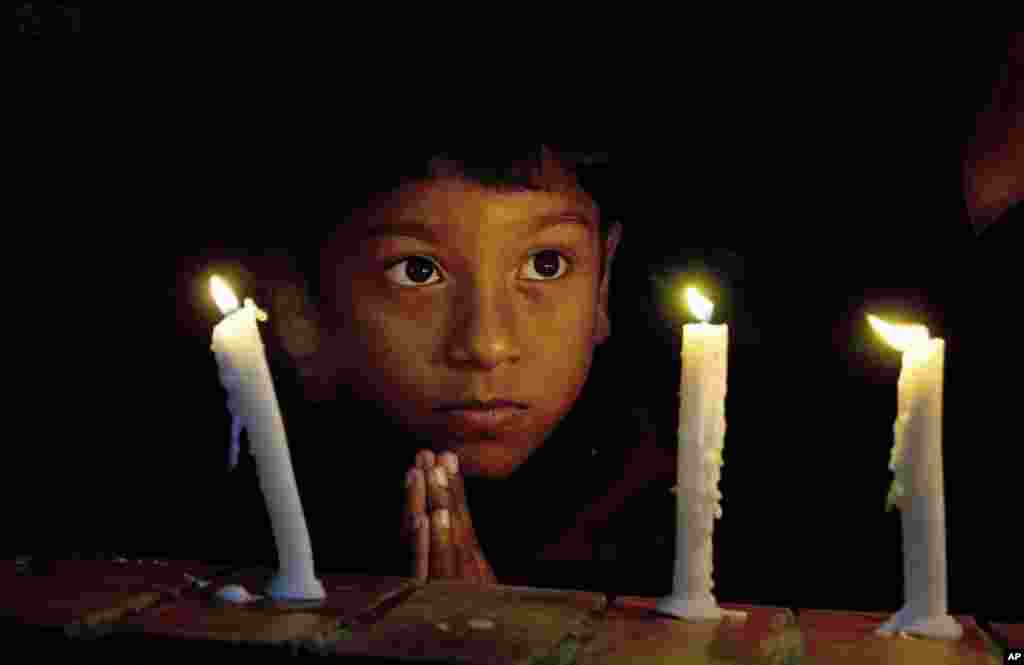 A boy prays during a candlelight vigil for victims of Paris attacks, at St. Thomas Church in Islamabad, Pakistan.