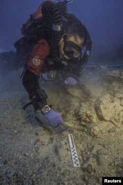 A diver works next to skeletal remains found at an ancient shipwreck near the island of Antikythera, Greece, Sept. 6, 2016.