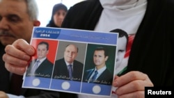 A Syrian national living in Beirut holds a ballot paper with pictures of the three presidential candidates, (from L-R) Maher Abdul-Hafiz Hajjar, Hassan Abdallah al-Nouri and Syria's President Bashar al-Assad, as she casts her vote ahead of the June 3 presidential election at the Syrian Embassy in Yarze, east of Beirut, Lebanon, May 28, 2014. 
