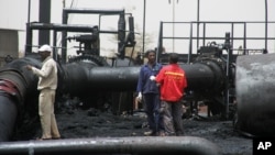 Sudanese workers inspect burnt out oil pipes at the oil-rich border town of Heglig, Sudan, April 24, 2012 (file photo). 