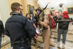 FILE - In this Jan. 6, 2021, file photo supporters of President Donald Trump are confronted by U.S. Capitol Police officers outside the Senate Chamber inside the Capitol in Washington. An Arizona man seen in photos and video of the mob wearing a fur hat w