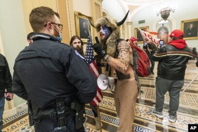 FILE - In this Jan. 6, 2021, file photo supporters of President Donald Trump are confronted by U.S. Capitol Police officers outside the Senate Chamber inside the Capitol in Washington. An Arizona man seen in photos and video of the mob wearing a fur hat w