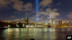 Pancaran sinar biru terlihat memancar dari balik jembatan Brooklyn dan bangunan sekitar kompleks World Trade Center, New York (10/9). "Tribute in Light" ini dinyalakan untuk mengenang tragedi serangan teroris 11 September 2001 di kota ini.