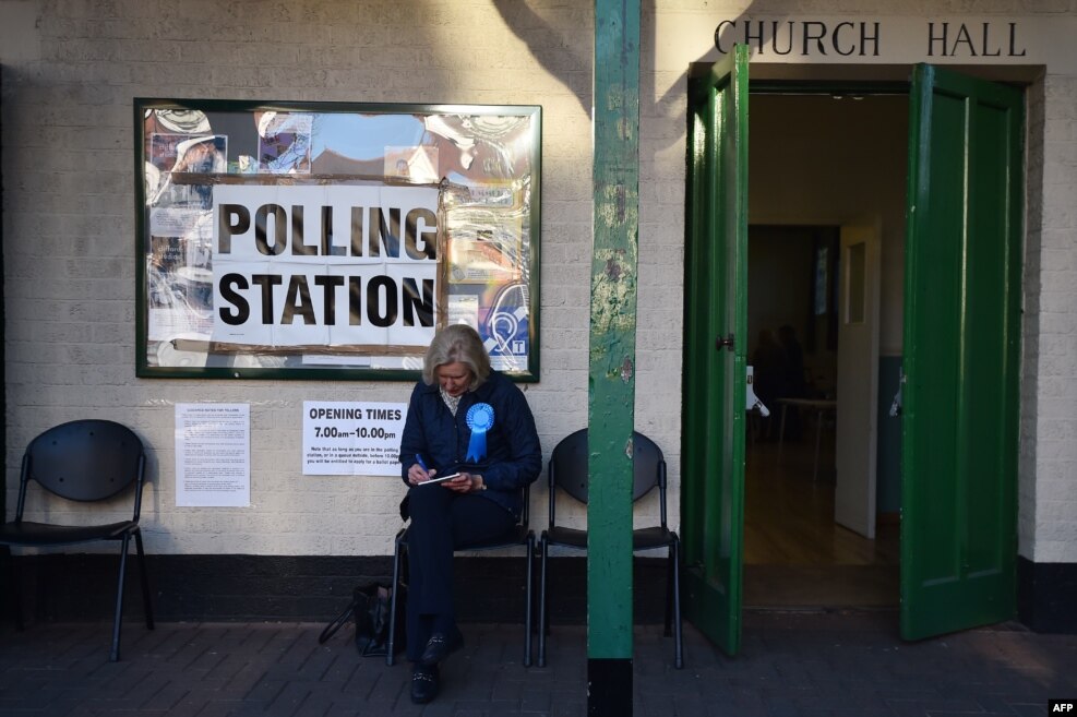 A representative of Britain's Conservative party sits outside a Polling Station in Barnes, south-west London.