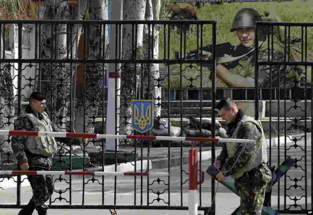 Ukrainian soldiers stand guard at the gate of a military base in the port of Kerch, Ukraine, March 3, 2014. 