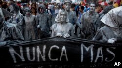 Las actrices que representan a las madres de la Plaza de Mayo, tienen una pancarta que lee en español: "nunca más", durante una marcha marcando el 41 aniversario del golpe militar en Buenos Aires, Argentina, el viernes 24 de marzo de 2017.