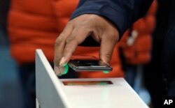 FILE - A shopper scans an Amazon Go app on a cellphone while entering an Amazon Go store, Jan. 22, 2018, in Seattle, Washington.