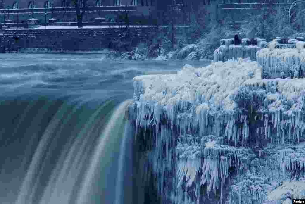 A lone visitor takes a picture near the brink of the ice covered Horseshoe Falls in Niagara Falls, Ontario, Canada.