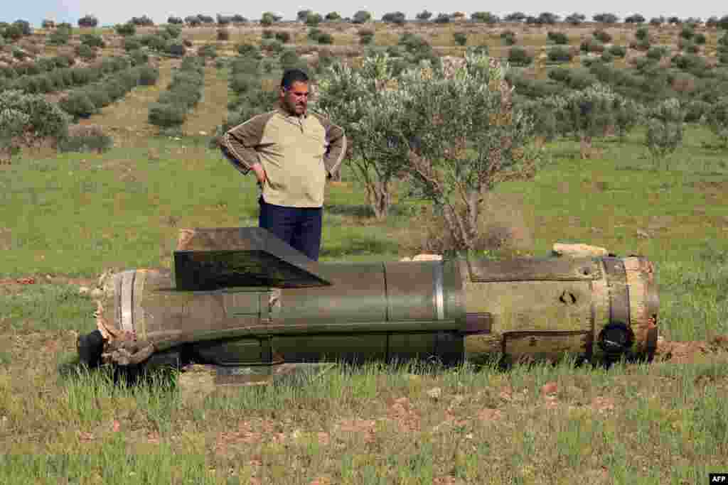 A Syrian man stands next to an unexploded ground-to-ground missile, fired by government forces on the southern Syrian city of Daraa.