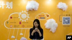 在北京的全球移动互联网大会上，一位女士在推广云服务的摊位前使用手机（2016年4月29日）
