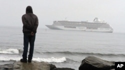 FILE - A man stands on the Bering Sea shore looking at the luxury cruise ship Crystal Serenity anchored just outside Nome, Alaska, Aug. 21, 2016. 