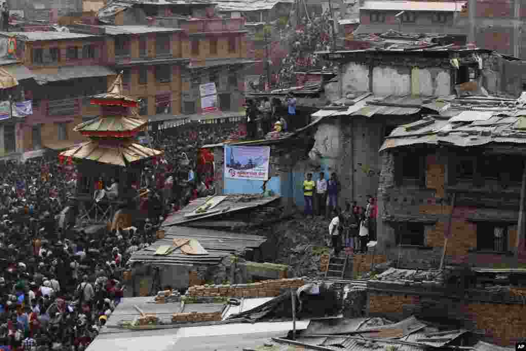 Nepalese devotees pull ropes tied to the chariot of Hindu god Bhairava, as houses destroyed by last year's earthquake are seen during Bisket Jatra festival in Bhaktapur.