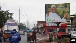 FILE - Motorbike taxis ride past a giant billboard of Mali's incumbent president, Ibrahim Boubacar Keita, that reads "the great Mali advance" in Bamako, Mali, July 18, 2018. As deadly attacks by extremists become more brazen in Mali, officials and citizens fear this month's presidential election will be at risk.