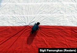 Seorang pria mempersiapkan bendera raksasa sebelum mengibarkannya pada perayaan hari kemerdekaan. (Foto: REUTERS/Sigit Pamungkas)