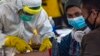 Para petugas kesehatan melakukan pemeriksaan kesehatan 156 pekerja migran Indonesia yang tiba dari Malaysia di Bandara Juanda, Surabaya, 7 April 2020. (Foto: AFP)