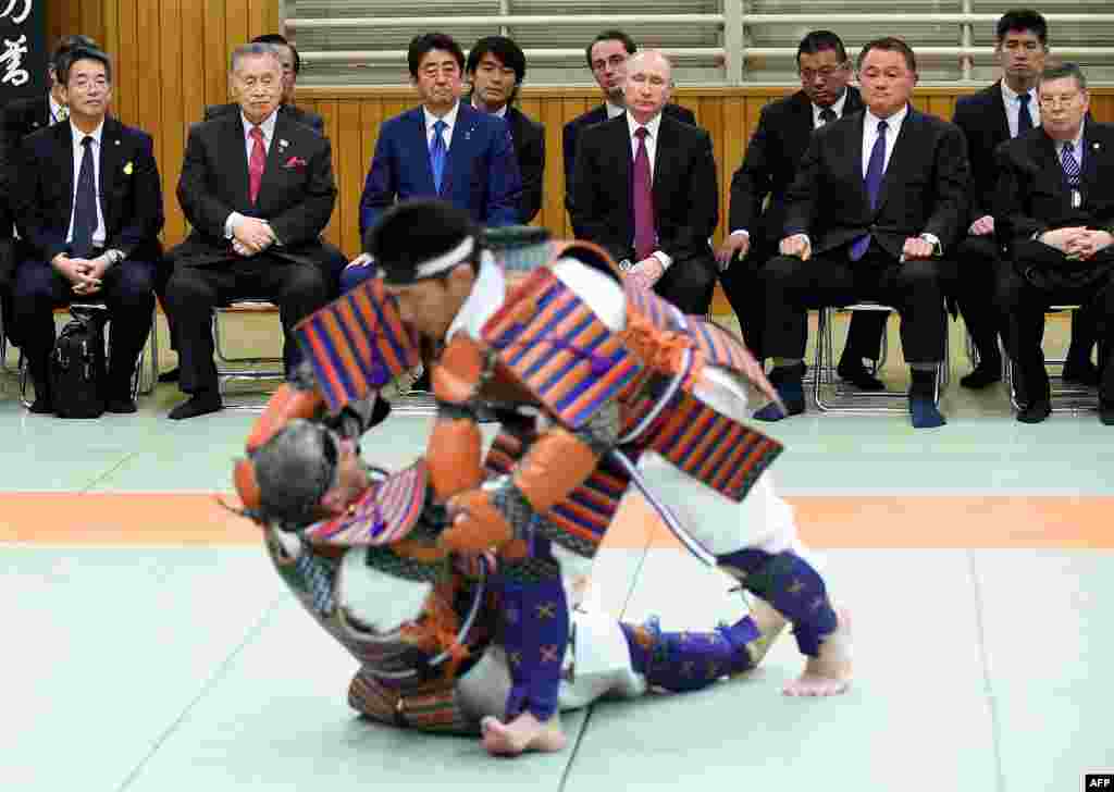 Russian President Vladimir Putin and Japanese Prime Minister Shinzo Abe watch a demonstration of ancient custom judo.