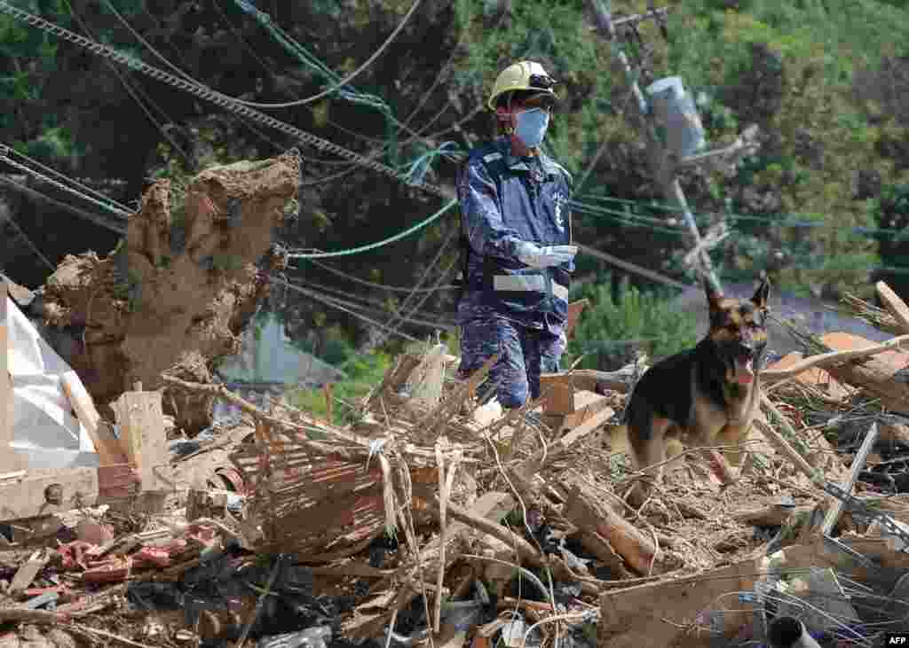 A member of the Maritime Self Defense Forces searches for missing persons at a flood-damaged site in Kure, Hiroshima prefecture, Japan. The toll in record rains that have devastated parts of Japan rose to 199, a top government spokesman said.