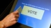 FILE - An elections official demonstrates a touch-screen voting machine at the Fairfax County Governmental Center in Fairfax, Virginia.