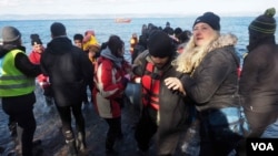 Volunteers and aid workers help refugees get to shore after they landed on the northern part of the island of Lesbos, Greece, Jan. 20, 2016. (H. Elrasam/VOA)