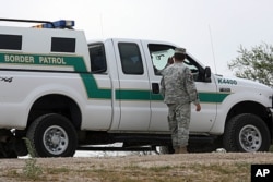 In this April 19, 2011 photo, a National Guardman talks with U.S. Border Patrol agents stationed along the Hidalgo International Bridge in Hidalgo, Texas.