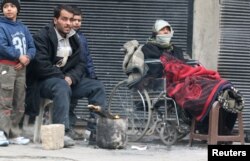People warm themselves around a fire while waiting to be evacuated from a rebel-held sector of eastern Aleppo, Dec. 17, 2016.