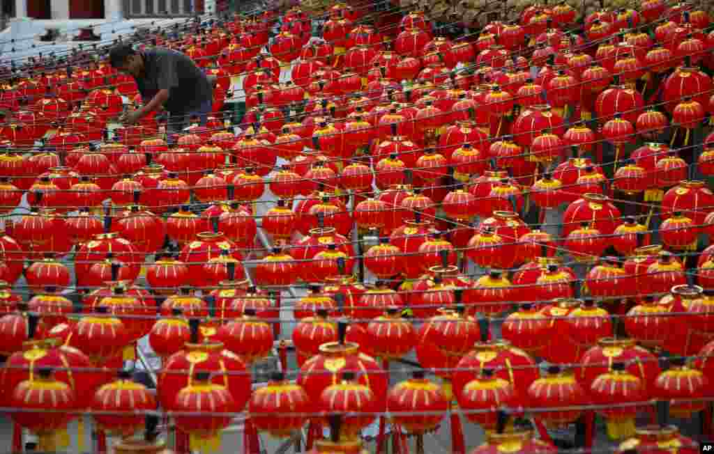 A worker adjusts Chinese traditional lanterns for the upcoming Chinese New Year at a temple in Kuala Lumpur, Malaysia.