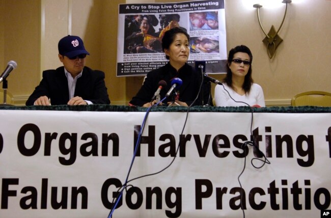 FILE - Dr. Wenyi Wang (C) holds a press conference with others, who preferred not to be identified, in Arlington, Virginia, April 26, 2006, about her having interrupted Chinese President Hu during his speech at the White House in Washington. Wang said she interrupted Hu to bring global attention to the organ harvesting from living Falun Gong practitioners in China.