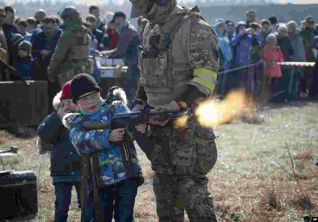 러시아 상트페테르부르크 외곽에서 열린 군사박람회에서 한 교관이 어린이들의 칼라슈니코프 자동소총 사격 체험을 돕고 있다. 소총에는 공포탄이 들어있다.