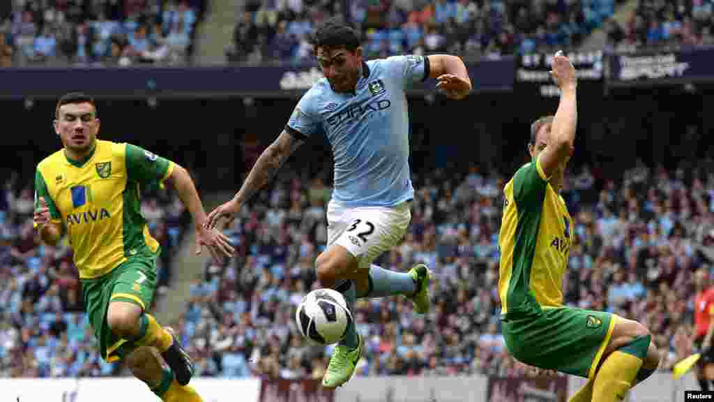 Norwich City's Steven Whittaker (R) and Robert Snodgrass (L) challenge Manchester City's Carlos Tevez (C) during their English Premier League soccer match in Manchester, May 19, 2013.