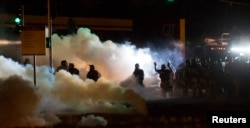 Riot police clear a street with smoke bombs while clashing with demonstrators in Ferguson, Missouri August 13, 2014.