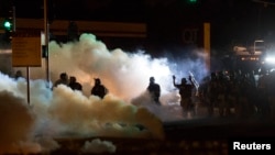 Polisi anti huru-hara membubarkan demonstran di Ferguson, Missouri (13/8).