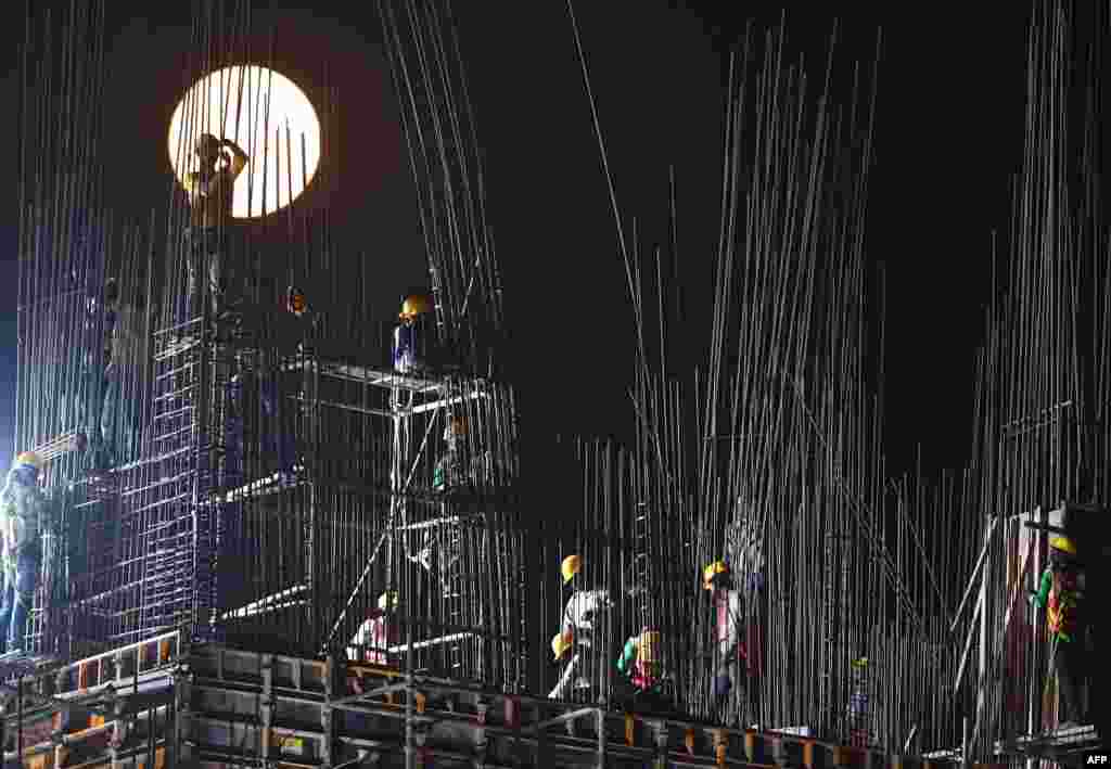 인도 콜카타의 건설현장에서 일하는 노동자들 너머로 &#39;슈퍼스노우문(Super Snow Moon)&#39;이 떠 있다.
