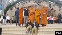 people pose with the buddhist monk Sutham Nateetong in front of Chicago's famous "bean" sculpture in Millenium Park.