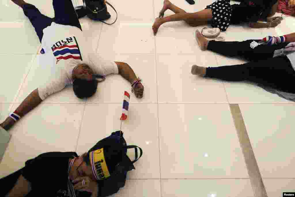 Anti-government protesters rest at the entrance of a building of the Finance Ministry after occupying it in Bangkok, Nov. 25, 2013.