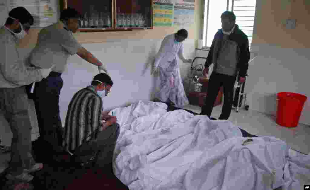 Medical staff inspect the bodies of victims at a hospital in Ghodegaon village in the western Indian state of Maharashtra, Wednesday, July 30, 2014