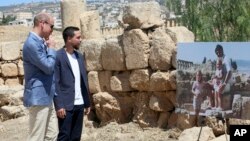 Britain's Prince William and Jordanian Crown Prince Hussein look at a photograph showing William's wife, the former Kate Middleton, her father Michael and younger sister Pippa in the ruins of the Roman city of Jerash in the 1980s in Jerash, Jordan, June 2